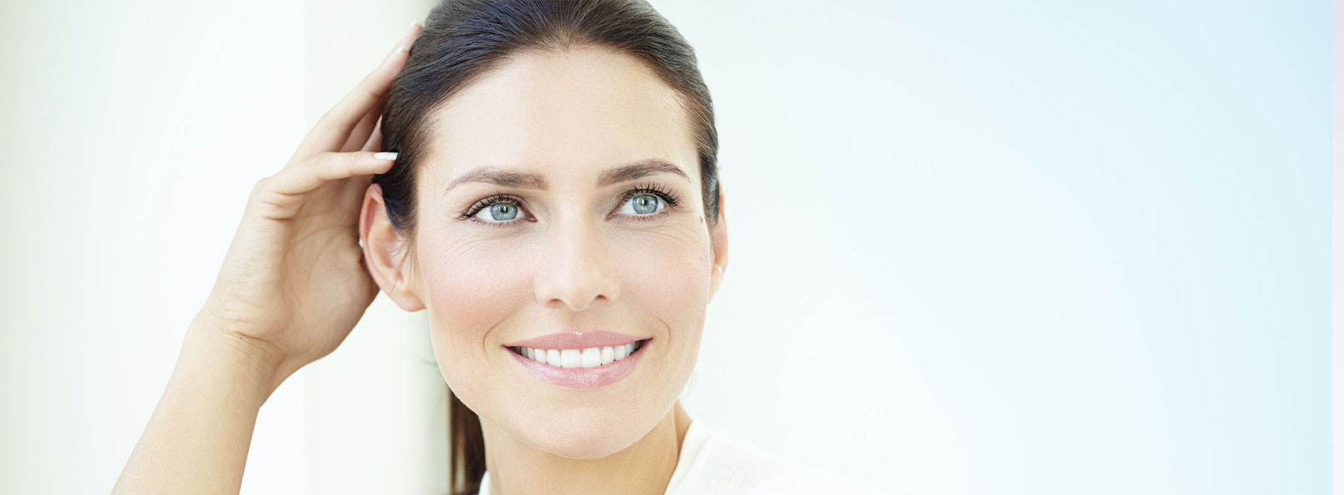 The image shows a close-up of a woman with blue eyes, smiling slightly, against a blurred background.