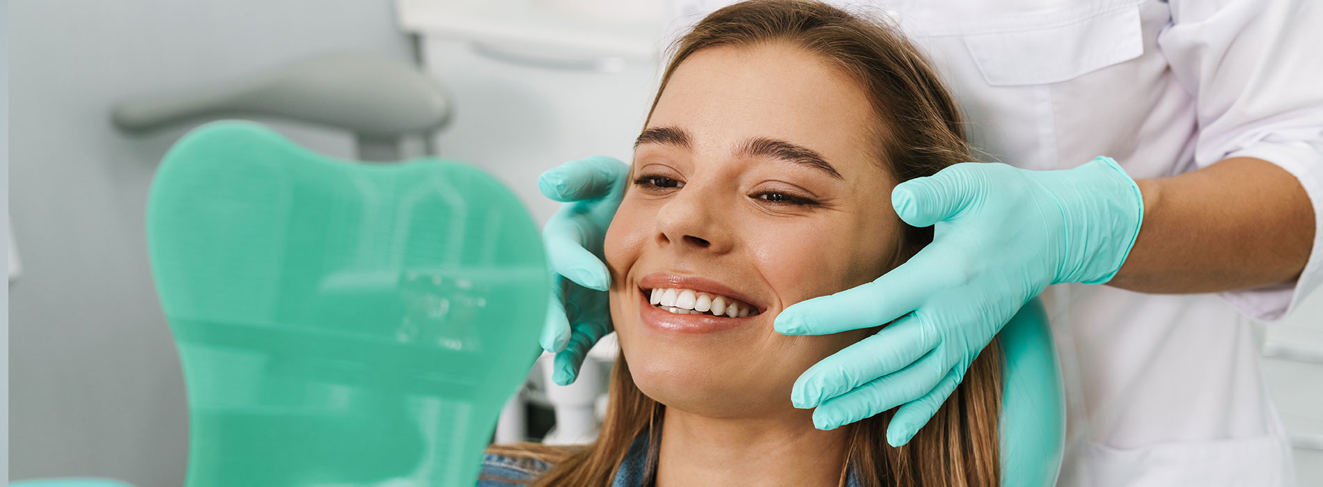 A woman sitting in a dental chair with a hygienist performing a cleaning procedure.