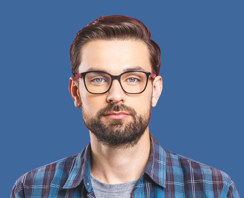 The image features a man with facial hair, wearing glasses and a plaid shirt, posing against a blue background.