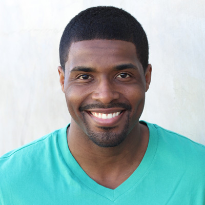 A man and woman are smiling at the camera, embracing each other with their arms around one another s shoulders.